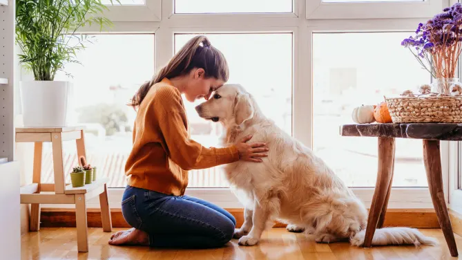 woman hugging her dog in her home