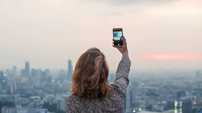 Woman outside taking a picture with her phone