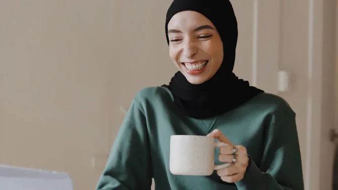 woman holding mug while on laptop