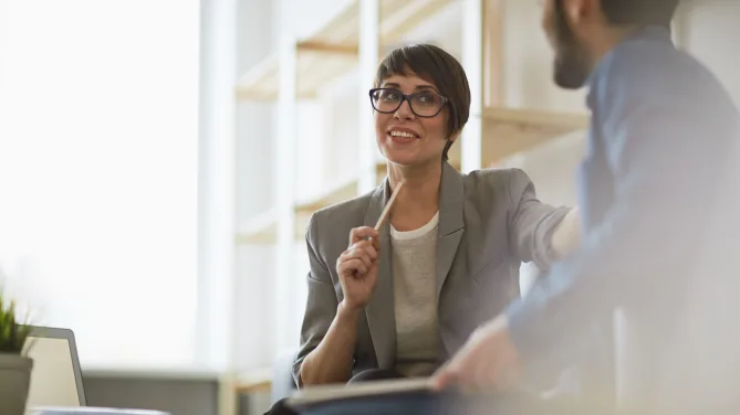 business woman talking to man with pen in hand