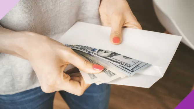 Photo of a woman holding an envelope with money, illustrating the 100-envelope challenge.