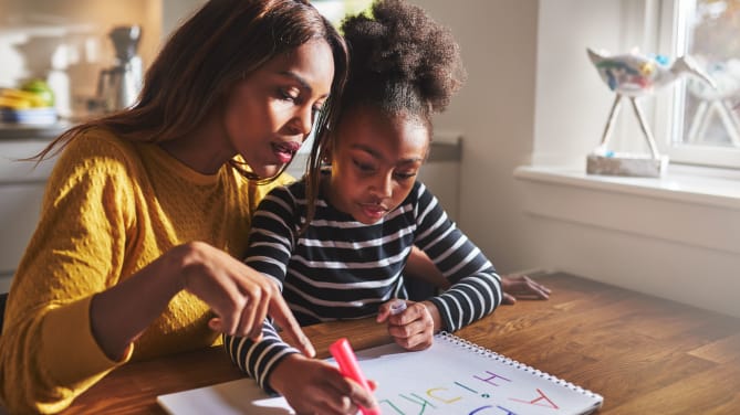 Mother helping her daughter write