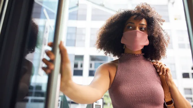 woman with mask opening door
