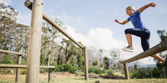 Woman leaping from one rock across chasm to another rock
