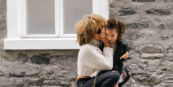 mother whispering in her daughter's ear