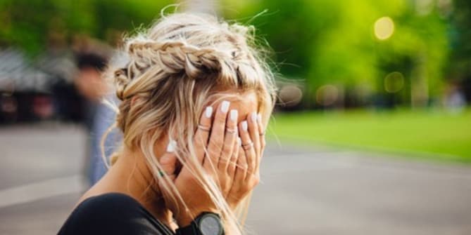 shy woman hiding her face in her hands
