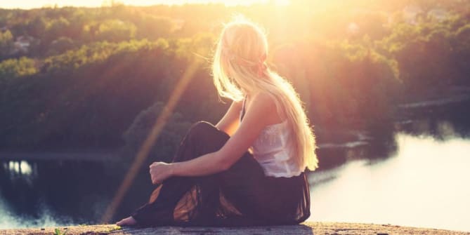 woman sitting by a lake