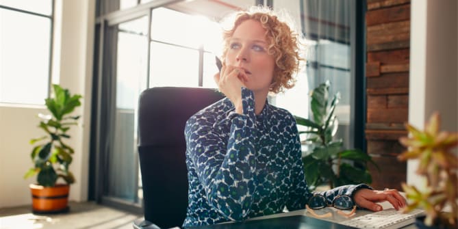 woman thinking with a notepad in front of her