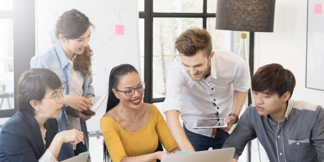 diverse group of employees gathered around a laptop