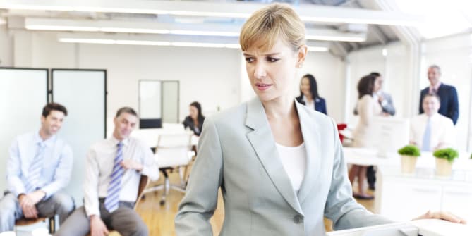 woman looking uncomfortable as male colleagues look on