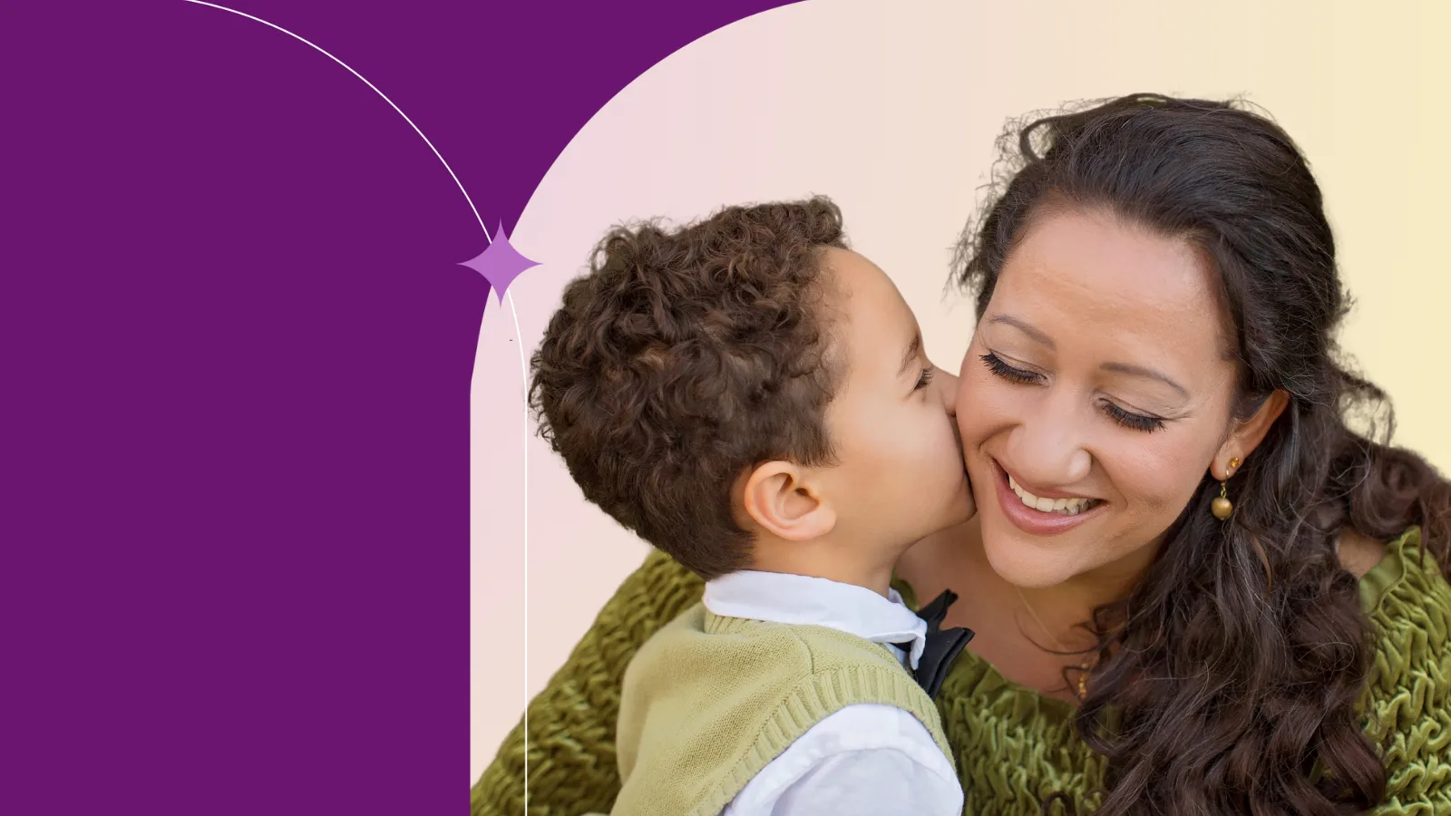 A person with long curly dark hair smiling while her child kisses her on the cheek. 