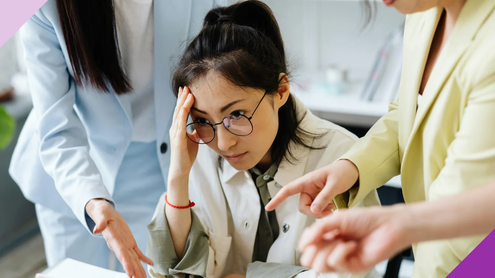 A woman at work looking upset while two women who look like her bosses say something to her, illustrating the quiet firing experience many workers face