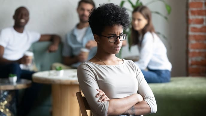 Black woman with crossed arms left out from conversation