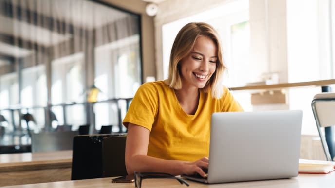 Woman smiling while typing on computer.