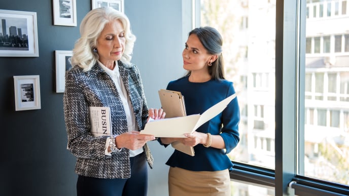 younger and older woman chatting at work