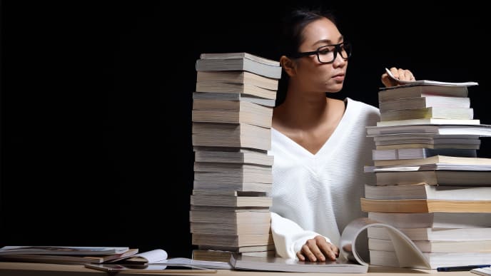 woman in an office with piles of books