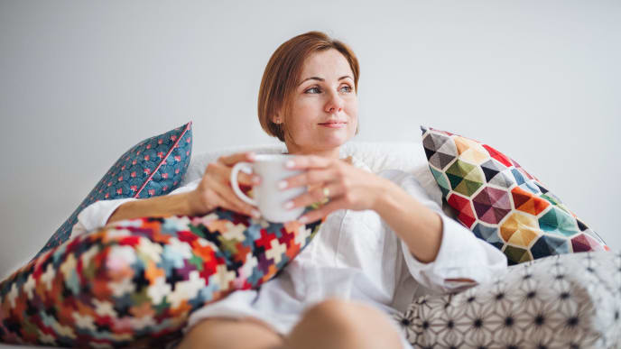 A woman smiles holding a mug of coffee