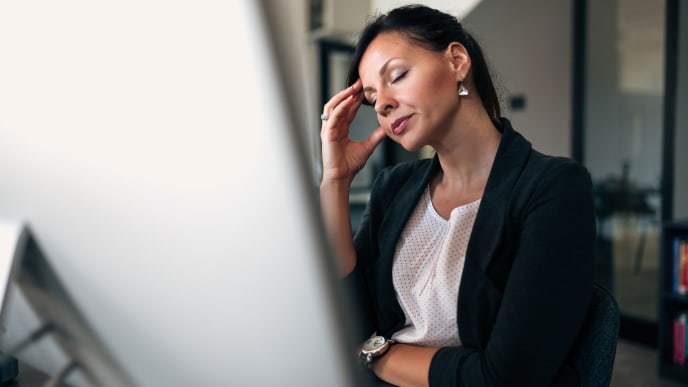 a woman closes her eyes in front of her computer screen