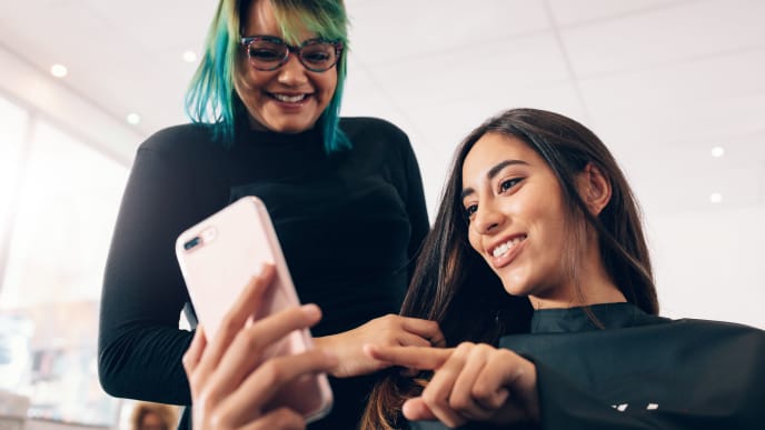 Women at salon looking at mobile phone