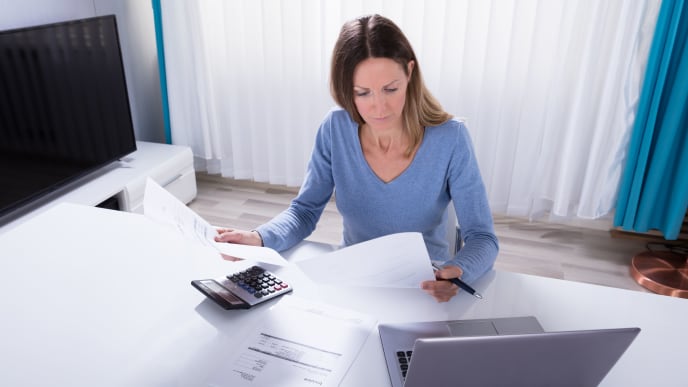woman calculating expenses on laptop and calculator