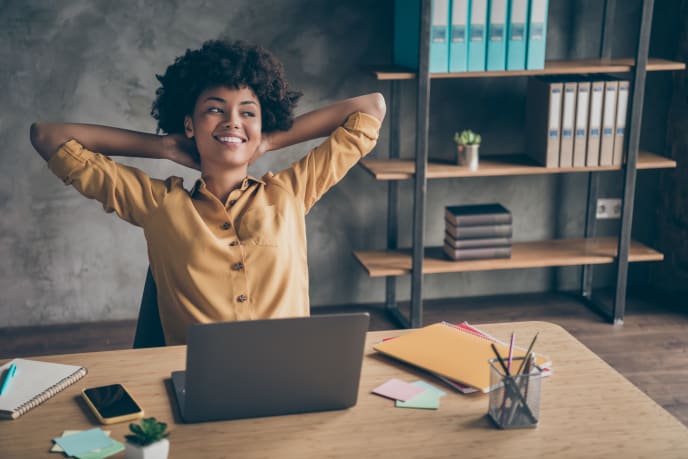 woman leaning back at her desk smiling
