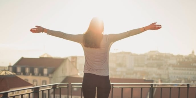 Negotiating flexible work schedules can have a freeing effect on your worklife balance. Woman with dark hair stands with arms wide and open while facing the sun.