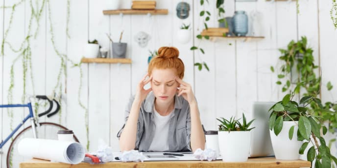 A stressed woman at work, head in her hands