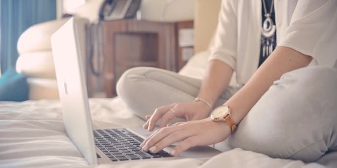 woman sitting on bed with a laptop