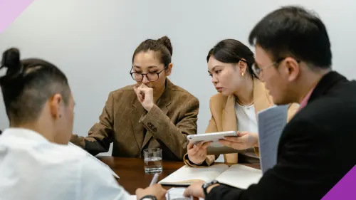 Two women looking uncomfortable at an office with two men to illustrate microaggressions women suffer at work