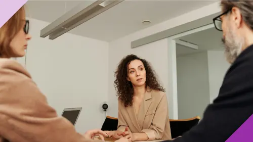 A woman at an office having a conversation with another woman and a man to illustrate how gaslighting happens in the workplace