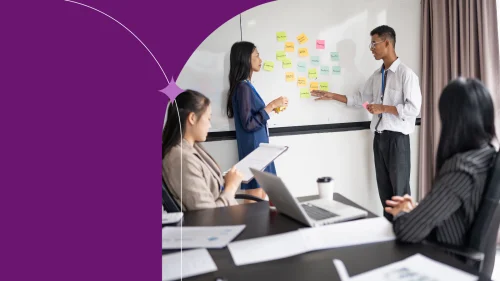 Coworkers collaborating during a team meeting with sticky notes on a whiteboard