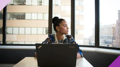 A woman looking sad, staring a window at her work desk to illustrate the impact of quiet firing has on women in the workplace