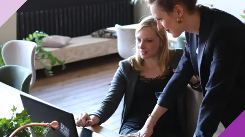 Two women at an office looking at an computer to illustrate the ways leaders can use AI in the workplace