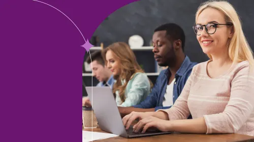 coworkers sitting working togther in an office, using laptops, smiling