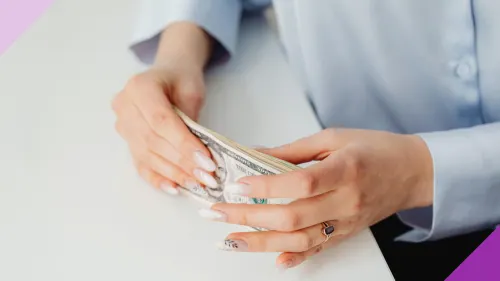 A woman's hands holding cash to illustrate the importance of learning the best way to save for kids' college