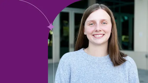 Alisa is standing and smiling, wearing a light blue sweater