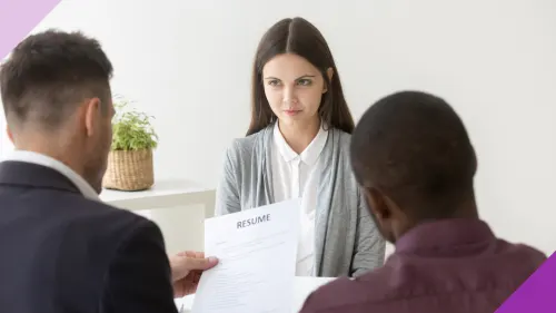 A woman at a job interview, being interviewed by two men, to illustrate the importance of reducing hiring bias