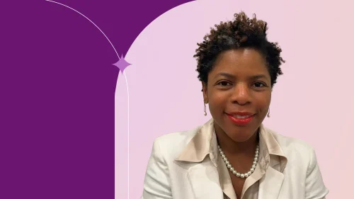 Althea is in front of a pink background, wearing a white jacket, smiling.