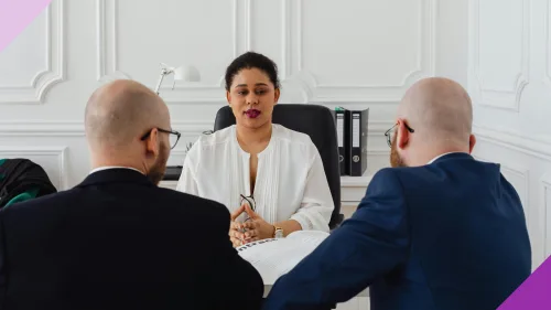 A woman having a meeting with two men to illustrate the importance of advocating for yourself at work as a woman