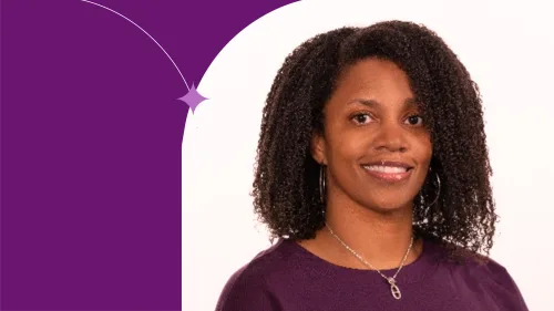 Chavaun standing, using a purple bluse, smiling