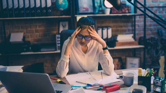 woman with a messy desk at work looking stressed