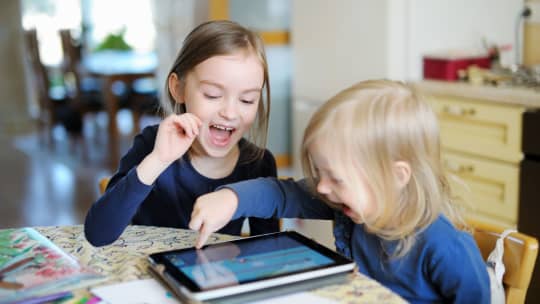 two kids laughing into tablet