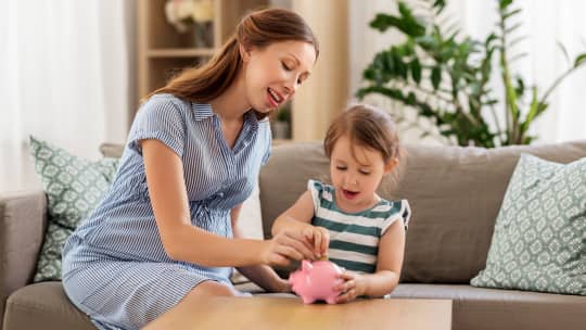 Woman and child putting money in piggy bank