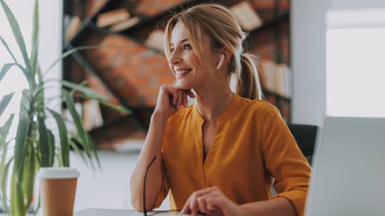 Woman smiling at desk while looking to the left.