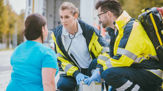 paramedics talking to woman outside of an ambulance