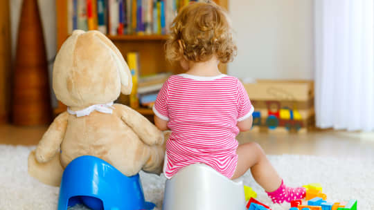 Child on potty next to stuffed animal