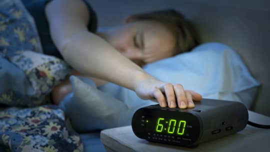 woman hitting the snooze button