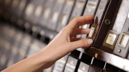 archivist reaching for file in archives