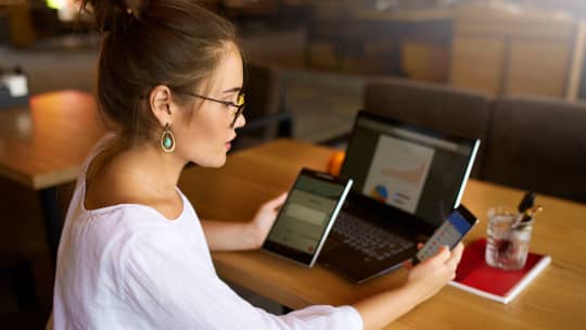 woman multitasking on phones and laptop