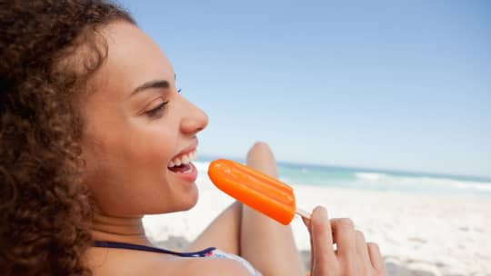 woman eating popsicle on the beach